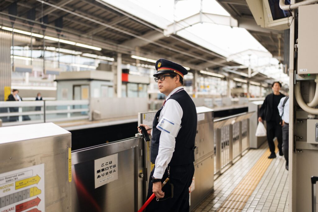 Security guard at a bustling Japanese train station during the day.